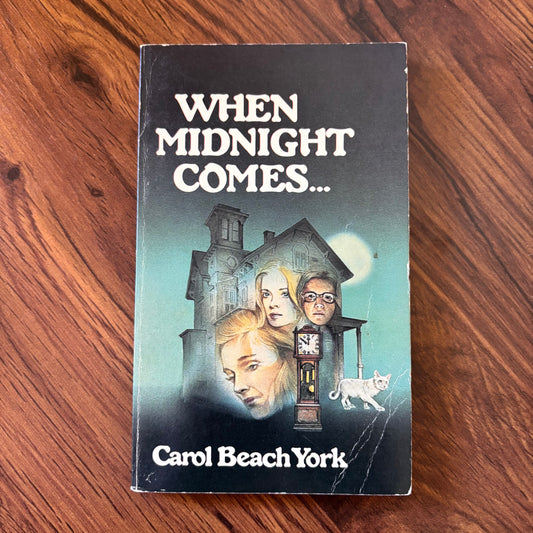 Cover of “When Midnight Comes” by Carol Beach York, 1979 Scholastic paperback edition, showing an eerie midnight scene with a spectral figure and an old house, typical of vintage horror novels.